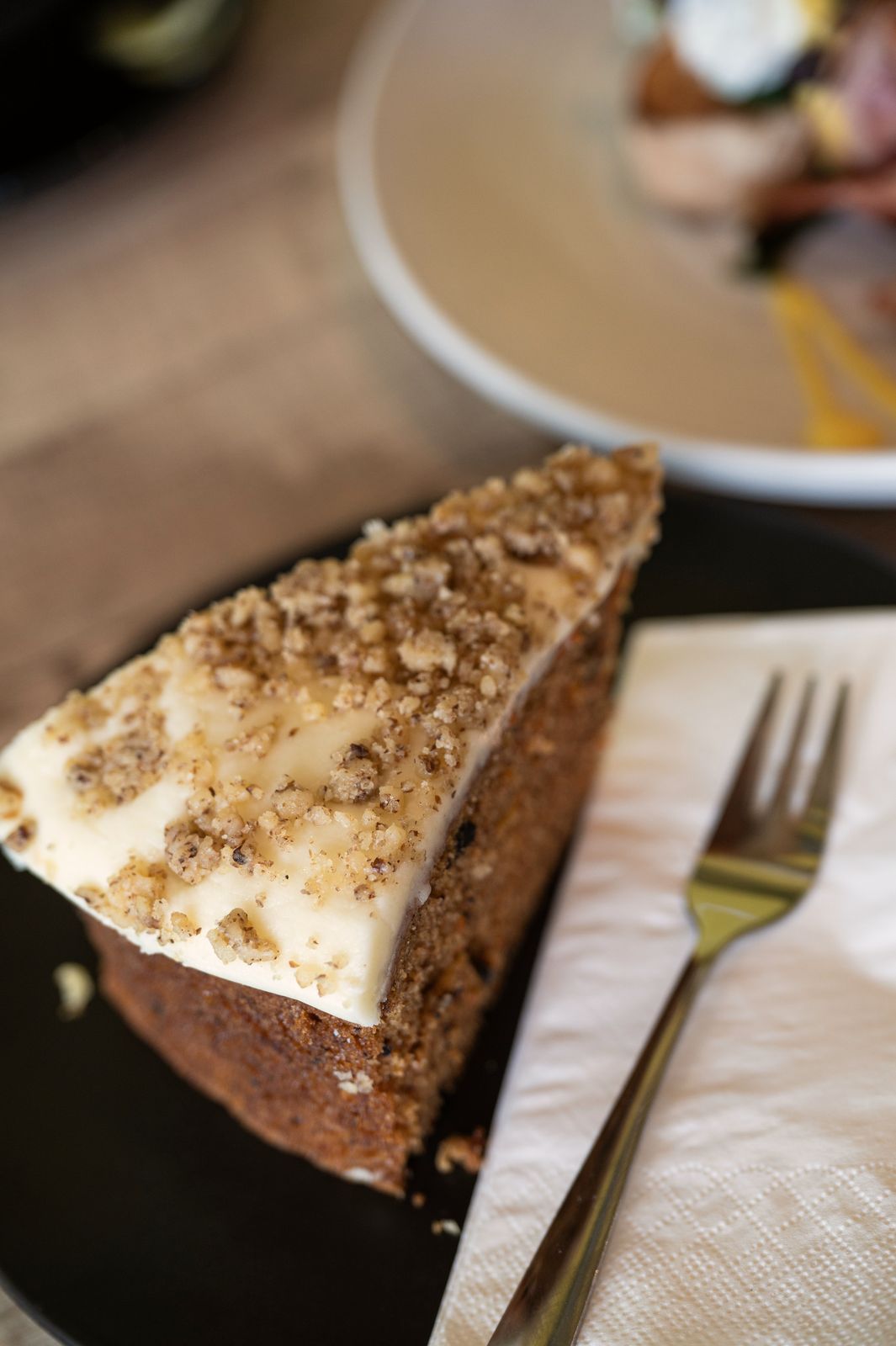 A slice of carrot cake with cream cheese icing and chopped walnuts