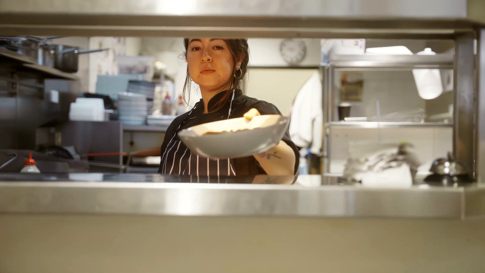 The chef handing a bowl across the pass in the Glenunga kitchen